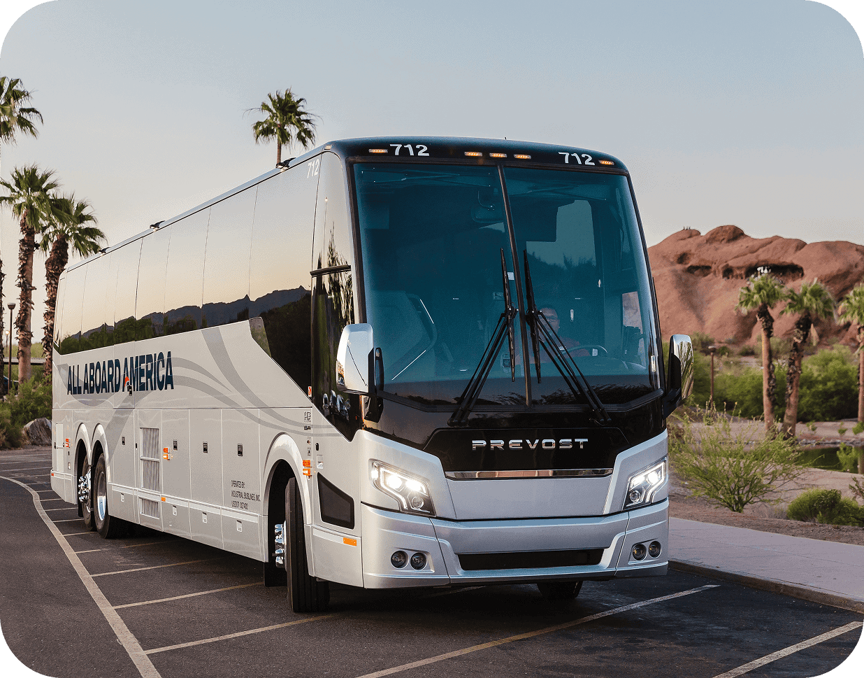 An All Aboard America bus parked in a parking lot with desert scenery in the background.