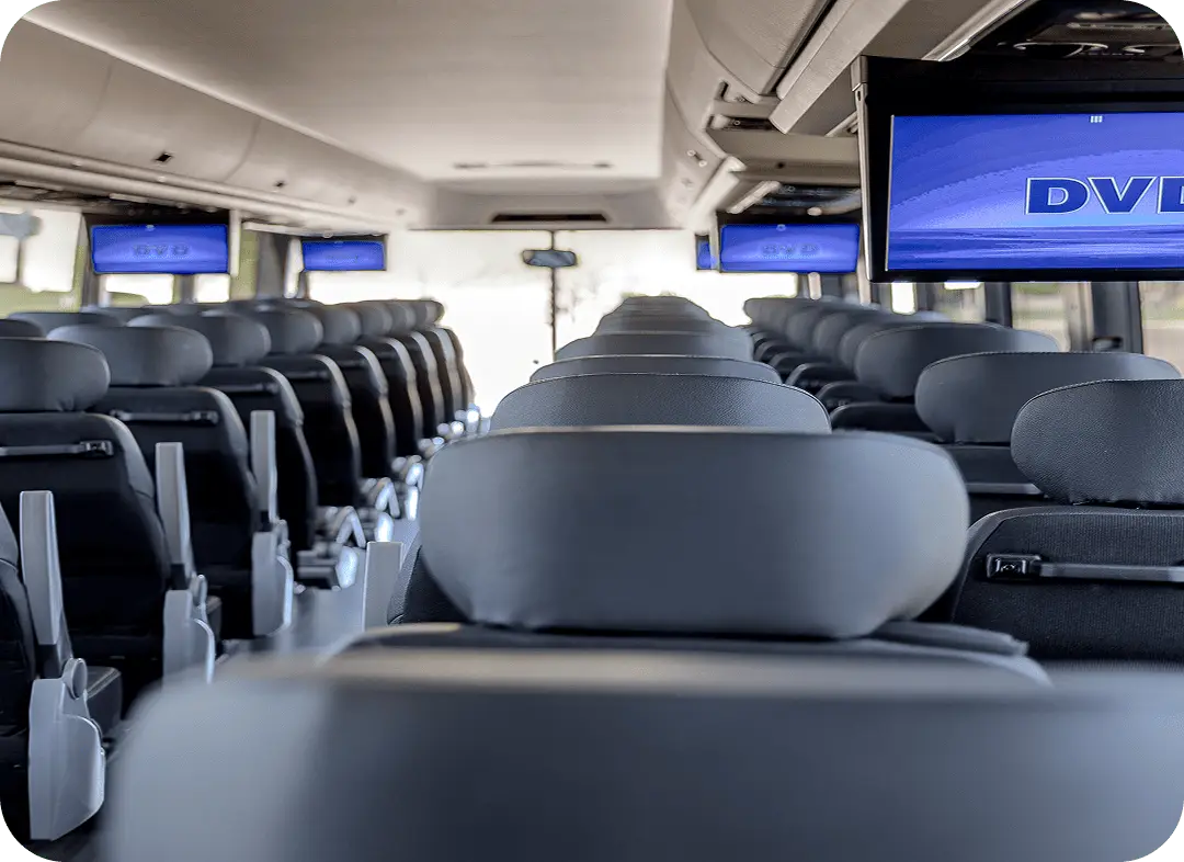 Interior of an All Aboard America motorcoach showing rows of seats with overhead DVD media screens