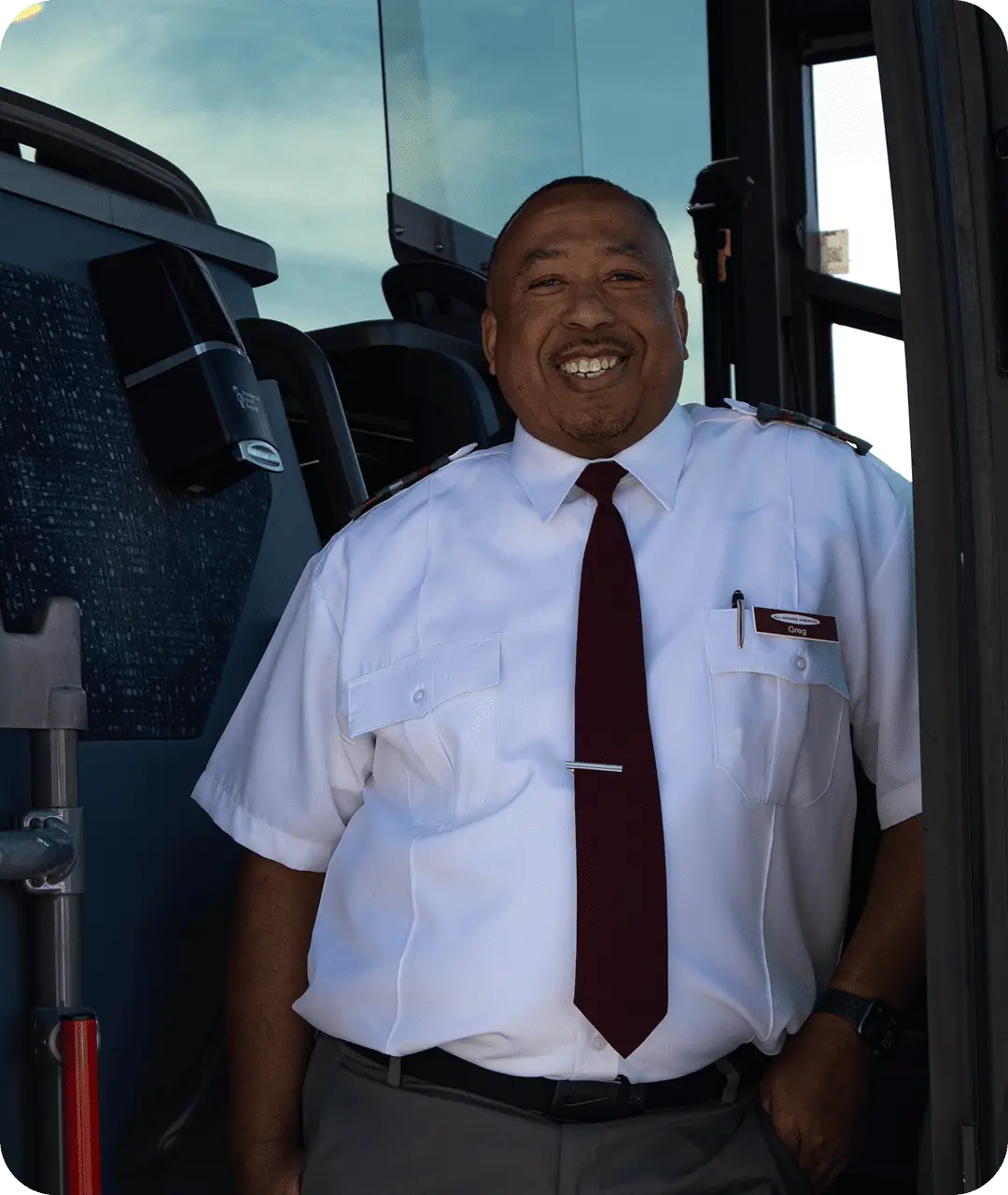 A smiling All Aboard America driver named Greg stands in the doorway of a motorcoach in uniform