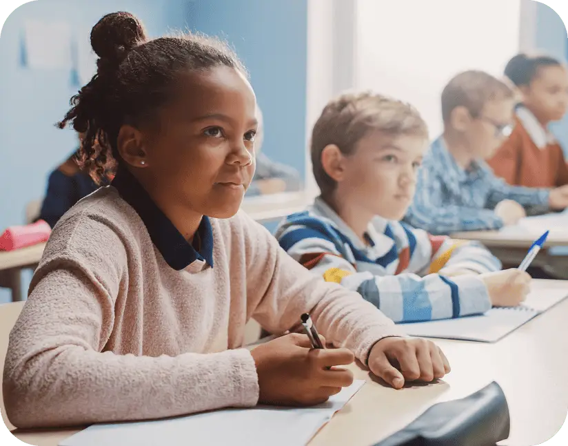 Elementary school students sit attentively at their desks in a classroom served by K-12 bus transportation