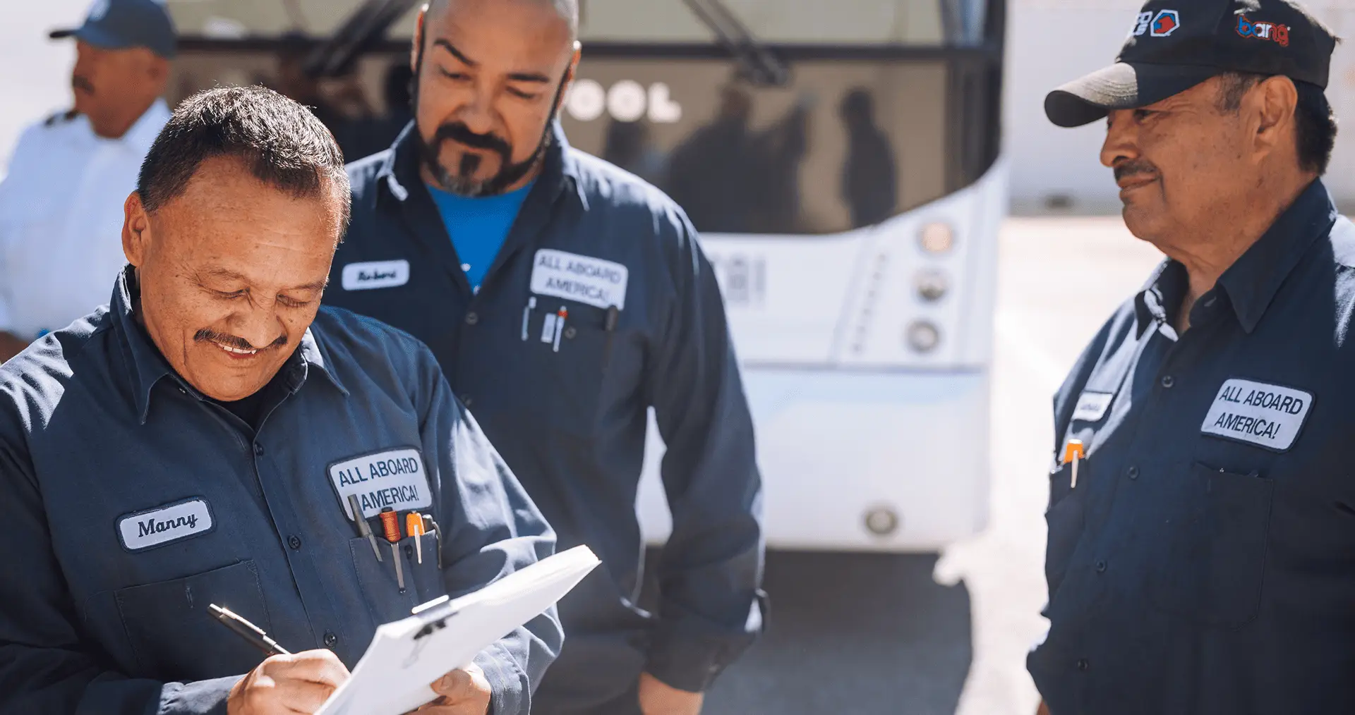a group of All Aboard America mechanics are reviewing a bus safety form