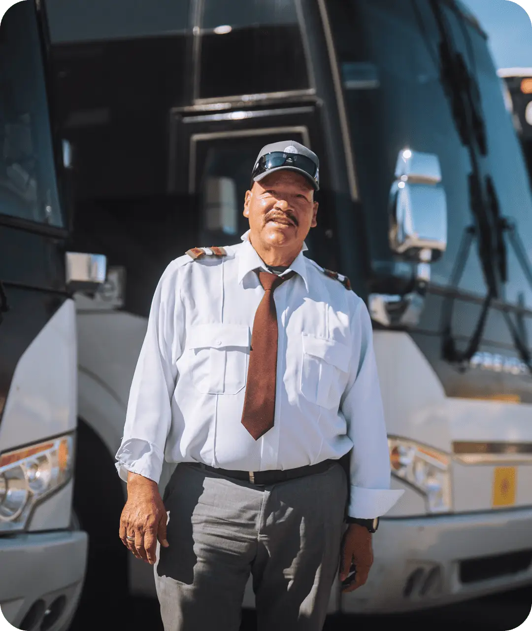 An All Aboard America driver in uniform and cap stands proudly in front of a Prevost motorcoach