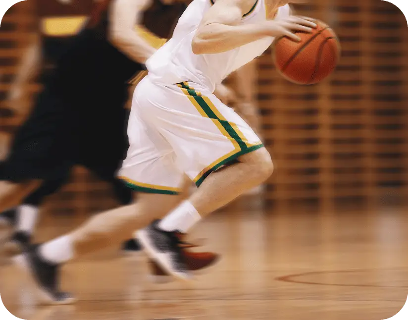 A basketball player dribbles the ball during a competitive game representing sports team travel transportation