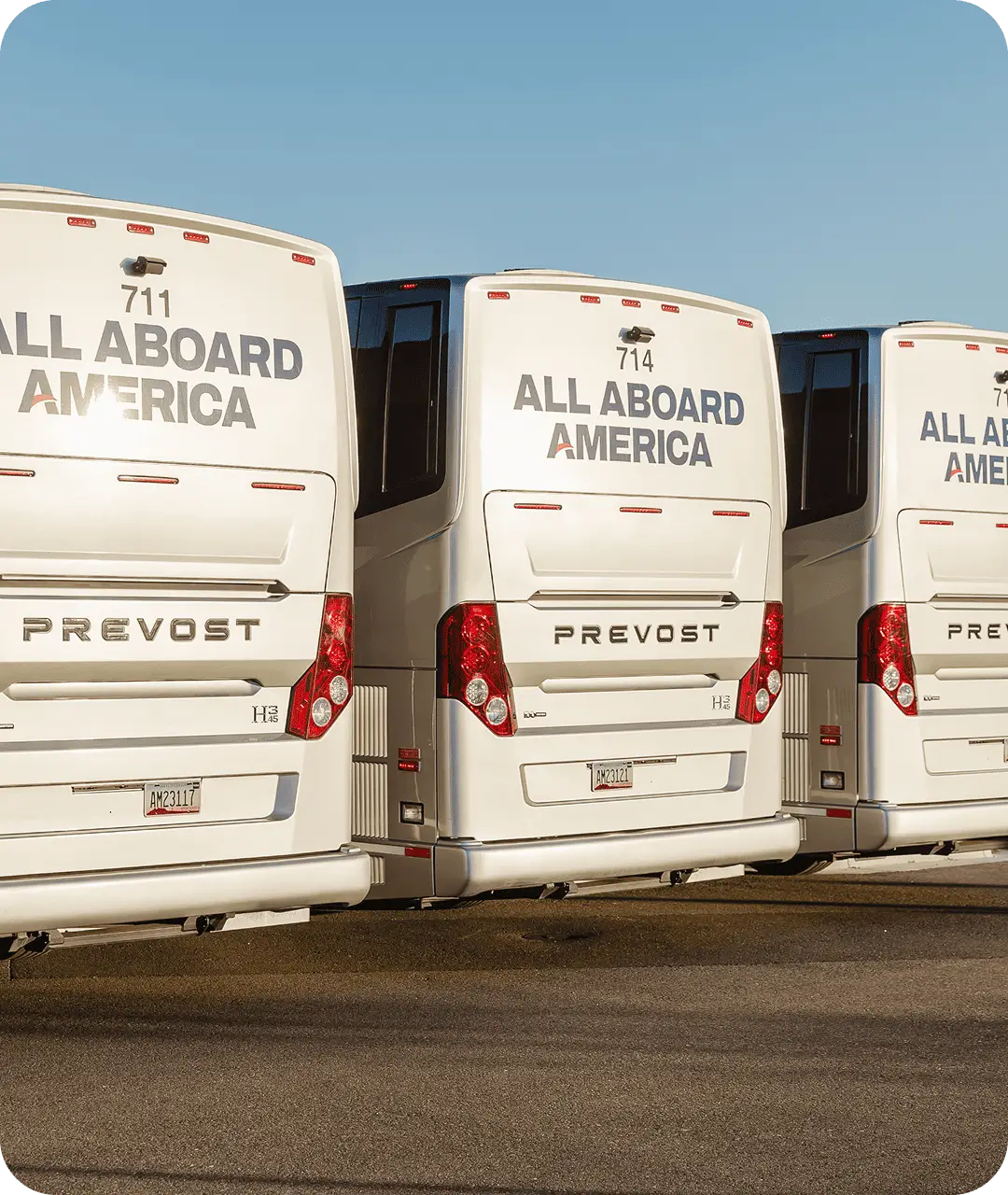 Rear view of three All Aboard America Prevost motorcoaches lined up displaying company branding