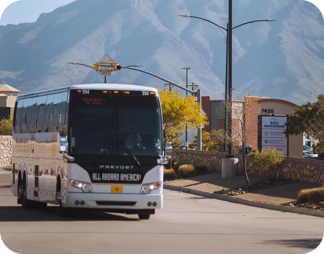 An All Aboard America Prevost bus running the Gold Route El Paso scheduled service with mountain scenery