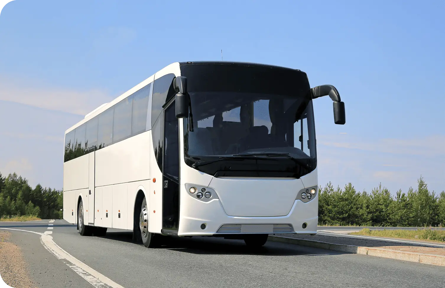 A full-size commercial motorcoach traveling on the highway against a blue sky