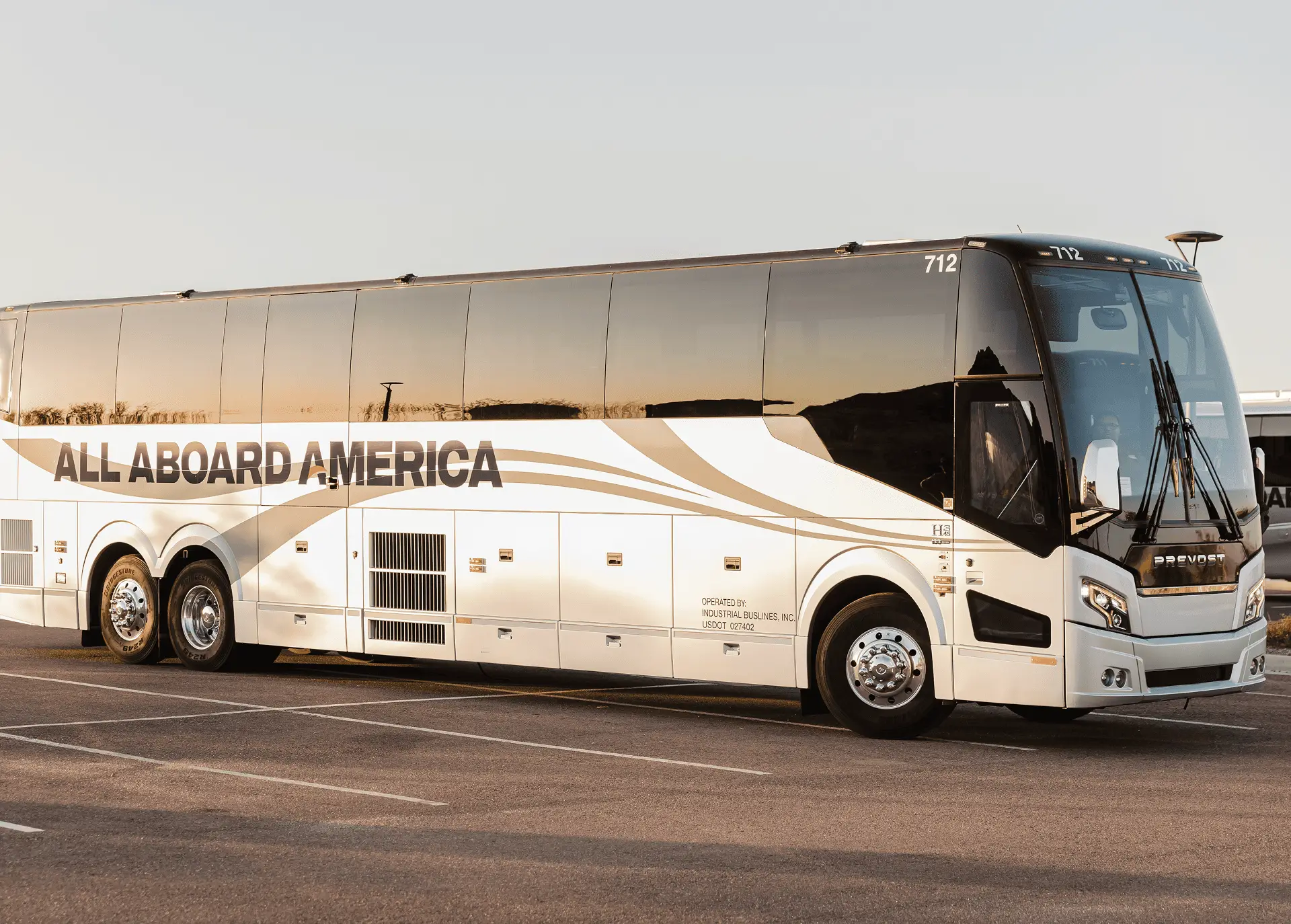 An All Aboard America Prevost motorcoach number 712 parked at golden hour in the fleet parking lot
