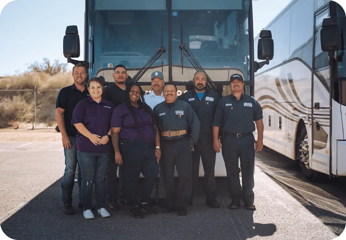 The All Aboard America team of drivers mechanics and staff pose together in front of a Prevost motorcoach
