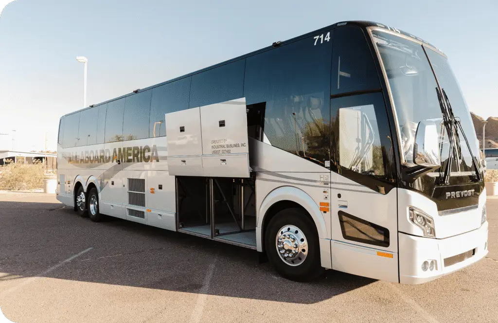 An All Aboard America Prevost motorcoach parked at dusk with desert scenery
