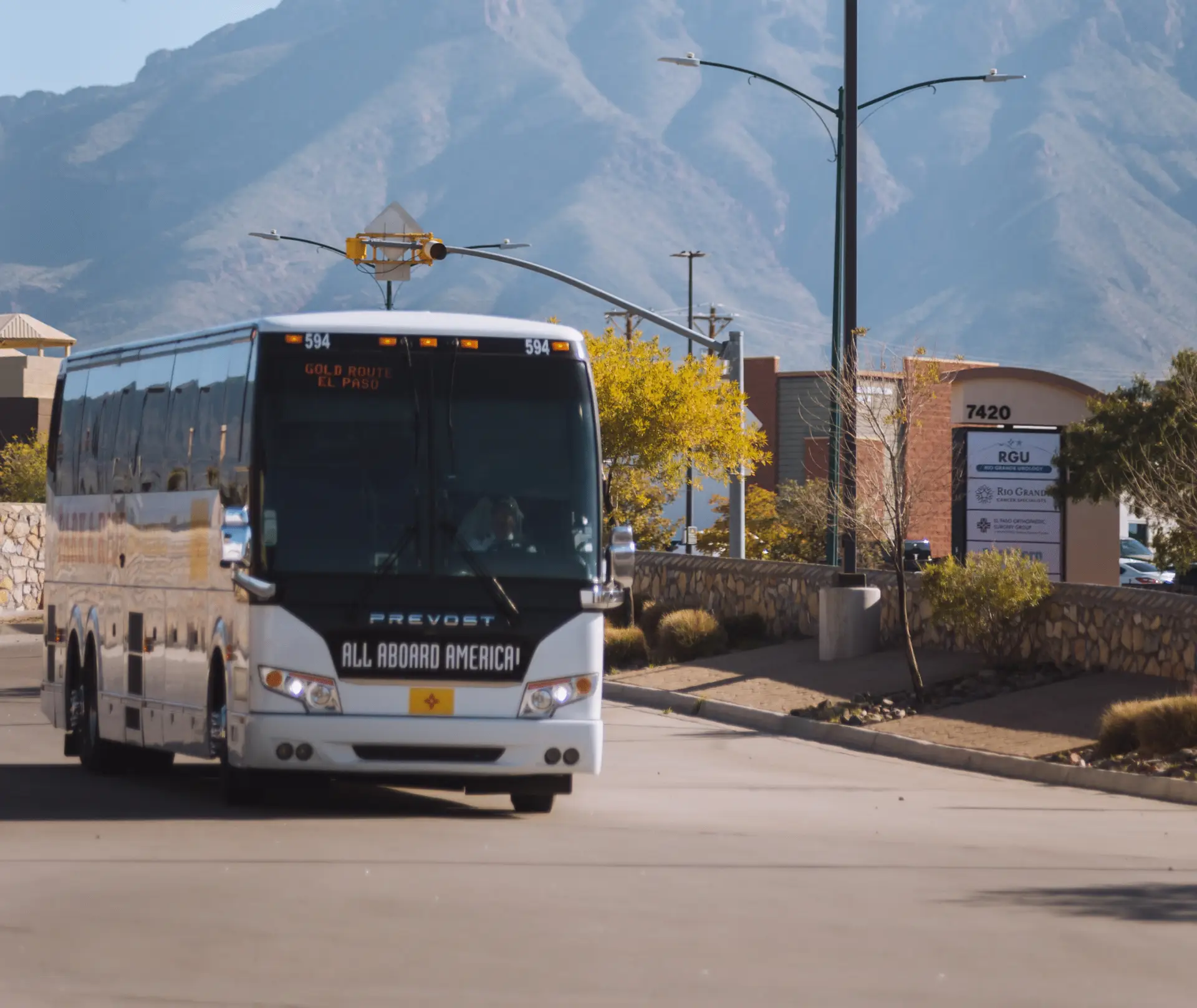 An All Aboard America Prevost bus operating the Gold Route in El Paso with Franklin Mountains in the background