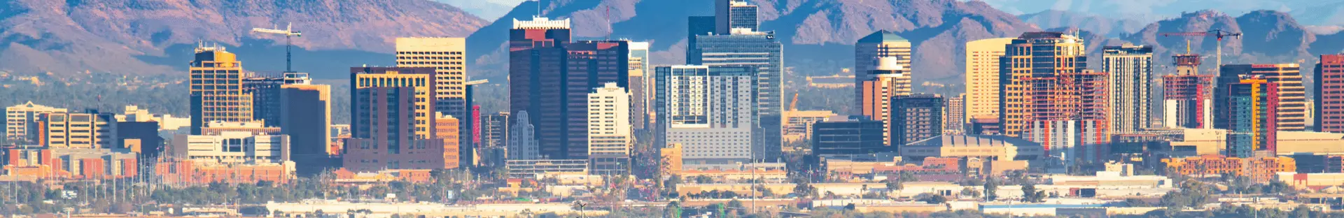 Panoramic daytime view of the Phoenix Arizona skyline with mountain backdrop home to All Aboard America bus operations
