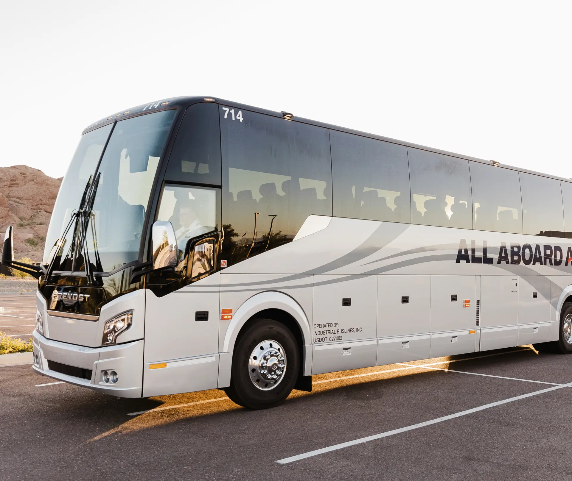 An All Aboard America Prevost motorcoach parked in a desert lot at golden hour ready for an over-the-road charter