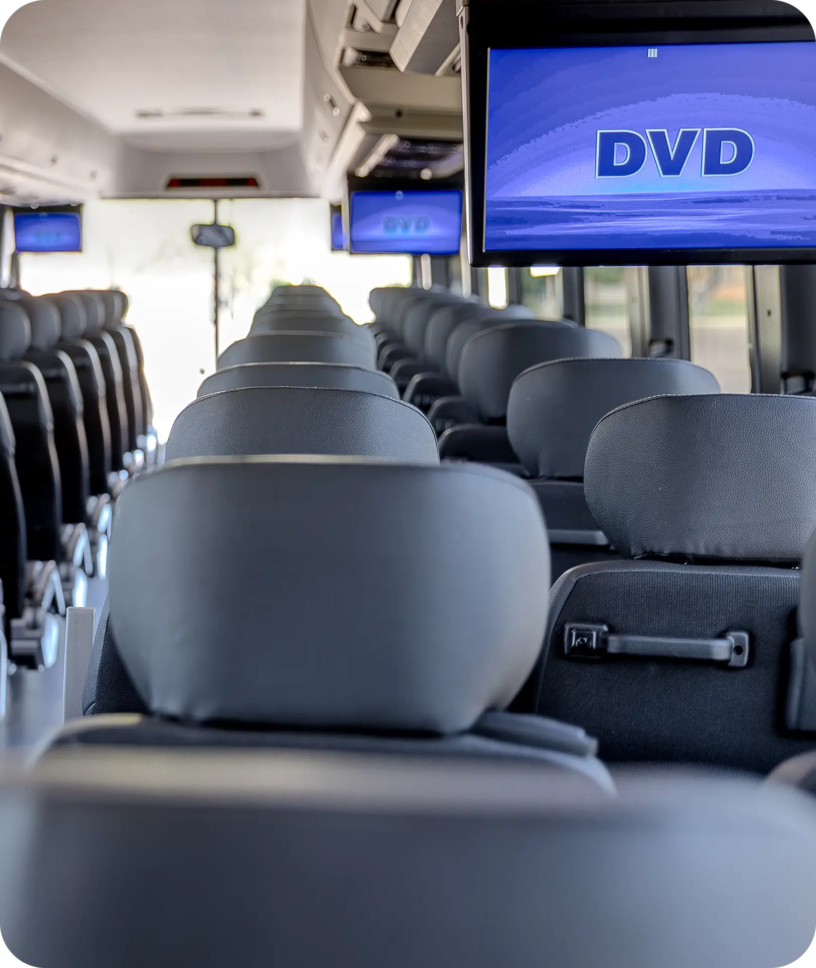 Interior of an All Aboard America charter bus showing rows of seats and overhead video screens for passengers