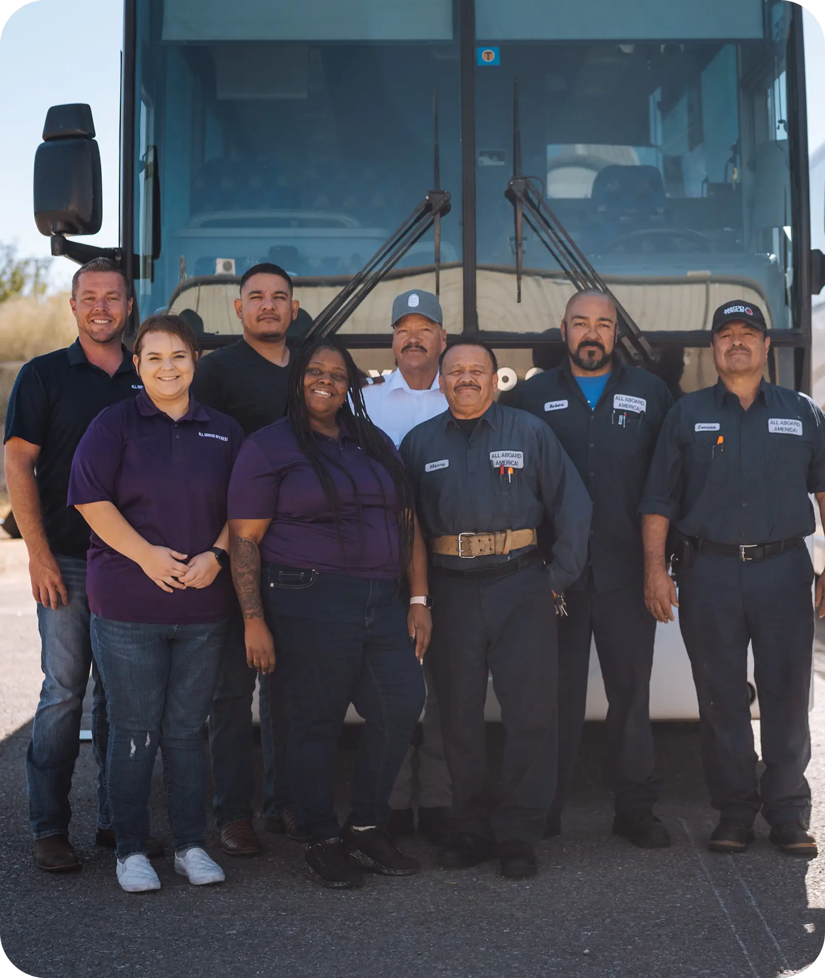 The All Aboard America team of drivers and staff pose together in front of a motorcoach at their depot