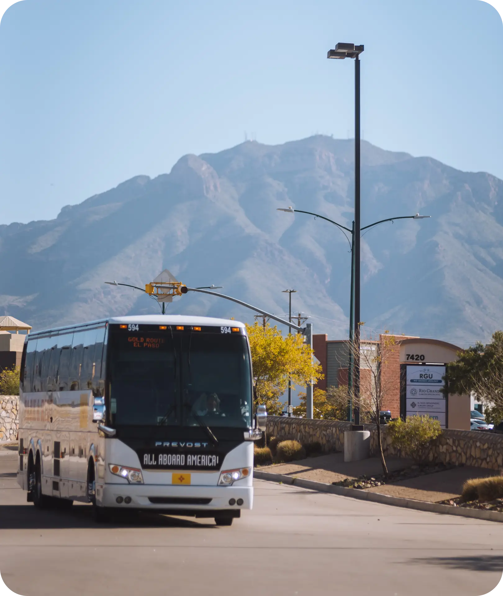 An All Aboard America Prevost bus running the Gold Route El Paso fixed transit service with mountain backdrop
