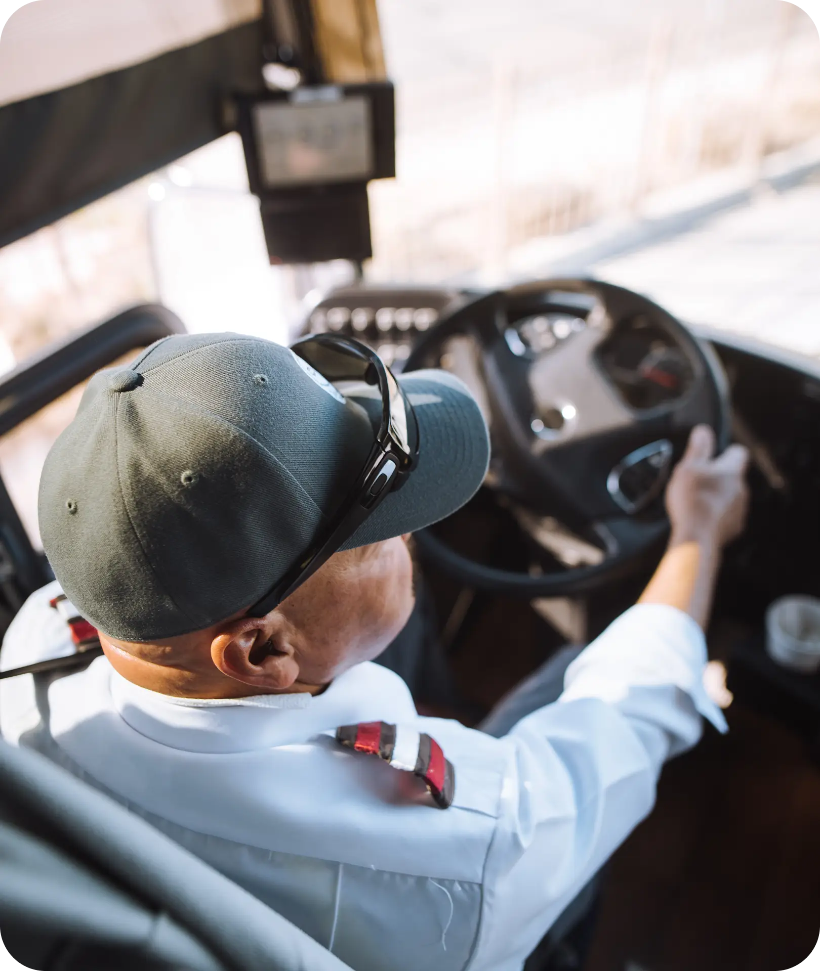An All Aboard America driver in uniform navigates a fixed route bus from the driver seat