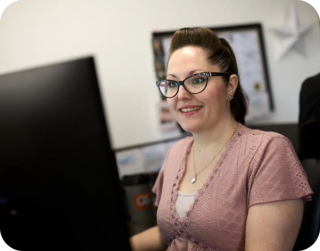 An All Aboard America staff member smiles at her desk while booking industrial workforce transportation services