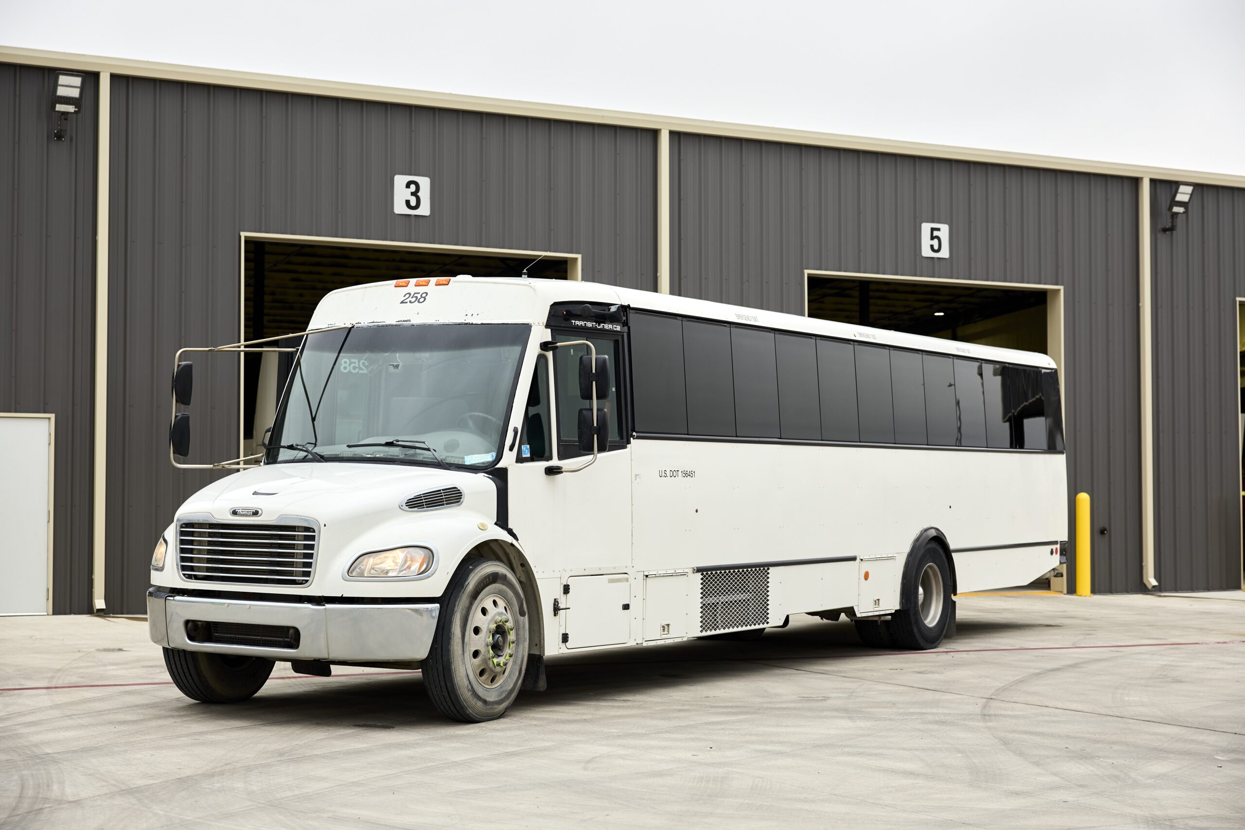 A full-size commercial motorcoach in front of a bus garage